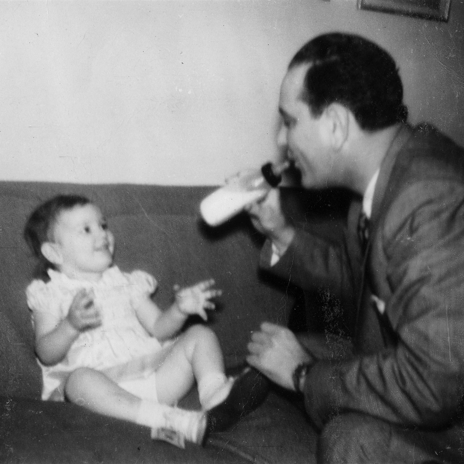 Lyndon Johnson shows his baby girl, Lynda, how to drink her baby bottle.
